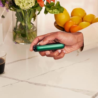 Hand holding a Ploom device with Amazon Green Front Panel

