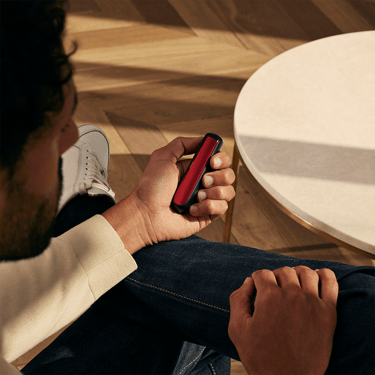 Lava Red Ön Panele sahip bir Ploom cihazını tutan bir erkek