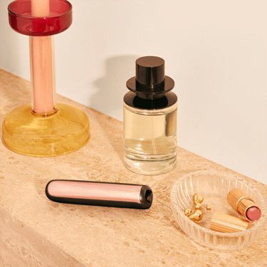 Makyaj masası üzerinde duran Rose Gold Özel Desenli Ploom AURA ön paneller.

