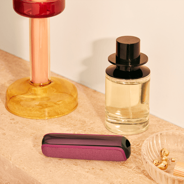 Ploom AURA Dark Orchid device placed on a table.
