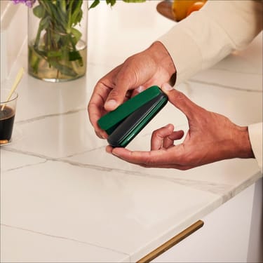 Hand placing an Amazon Green Back Cover on a Ploom AURA device